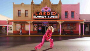 Outside the Laredo Comedy Club, the same young blonde Barbie, dressed in a striking hot pink outfit, is playfully posing on the side2 Outside the Laredo Comedy Club, the same young blonde Barbie, dressed in a striking hot pink outfit, is playfully posing on the side2